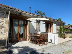 un patio con mesa y sombrilla en Fonclaire Holidays, en Mortemart