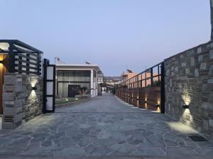 a walkway leading to a building with a stone wall at Olivujoj Villajoj - Deluxe Villa with Detached Pool House in Anavyssos