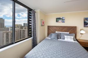 ホノルルにある2 Bedroom Corner Suite & Tropical Viewsのベッドルーム1室(ベッド1台、大きな窓付) +7枚の写真