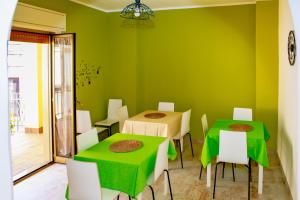 un comedor con 2 mesas y paredes verdes en MOKARTA B&B, en Catania