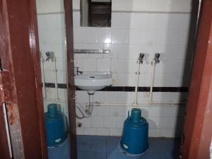 a bathroom with a sink and two blue barrels at Hotel Embassy in Shillong