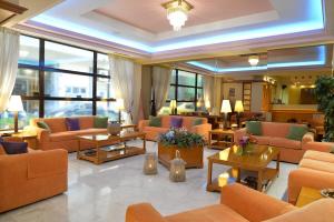 a lobby with orange couches and tables and windows at Victory Inn in Athens