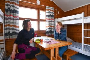 two women sitting at a table in a cabin at Kilpisjärven Retkeilykeskus Cottages in Kilpisjärvi