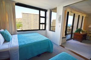 a bedroom with a bed and a large window at Waikiki Banyan 1909 Amazing Views and Just Steps to the Beach in Honolulu