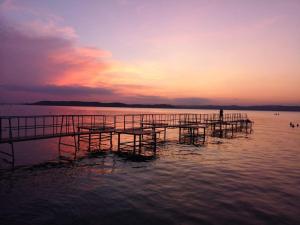 a person standing on a dock in the water at sunset at Vivienne Apartment in Zamárdi