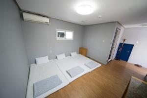 1 dormitorio con 1 cama blanca grande y suelo de madera en Beewon Guesthouse, en Seúl