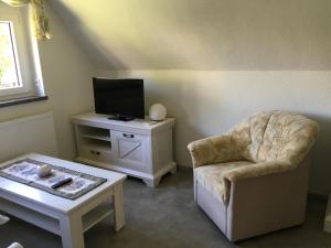 a living room with a chair a table and a tv at Ferienwohnung Möckel in Struppen
