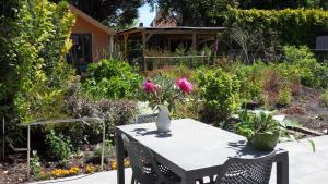 a table and chairs in a garden with a vase of flowers at Ambiance in Zierikzee