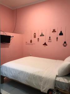 una camera con un letto bianco su una parete rosa di RoomZ Budget Residence a Semarang