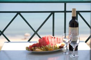 a plate of food with a bottle of wine and wine glasses at Lazaratos Hotel in Lixouri