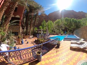 a resort with a swimming pool and mountains in the background at Kasbah Restaurant Amazir in Tinerhir