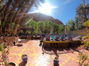 a patio with palm trees and a mountain in the background at Kasbah Restaurant Amazir in Tinerhir