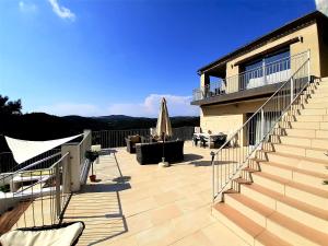 eine Terrasse mit Treppe und ein Haus mit Sonnenschirm in der Unterkunft Villa Paraiso - Piscina Privada & Relax in Olivella