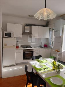 a kitchen with white cabinets and a table with chairs at Apartments Viktorija in Pula