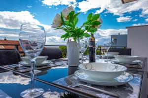 a table with wine glasses and flowers on a balcony at Apartmani Jasminka in Dramalj