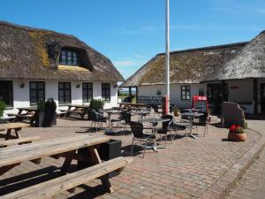 a patio with tables and chairs in front of buildings at Blåvandshuk Golf Hostel in Blåvand