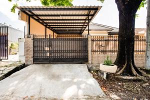 a black gate with a tree in front of a house at OYO 3398 Griya RM 19 Syariah in Surabaya