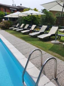 eine Reihe von Stühlen und Sonnenschirmen neben einem Pool in der Unterkunft Albergo Paradiso in Maccagno Superiore