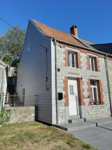 una casa con una puerta blanca y un edificio de ladrillo en Maison de campagne en pierre bleue-WIFI et parking, en Bousignies-sur-Roc