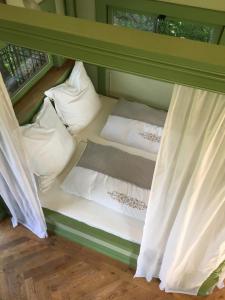 Bett in einem Zimmer mit Kissen und Fenster in der Unterkunft Baumhaus auf dem Kellerberg in Fischach
