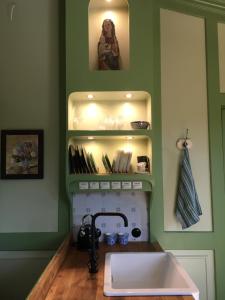 a kitchen with a sink and a shelf with items at Baumhaus auf dem Kellerberg in Fischach