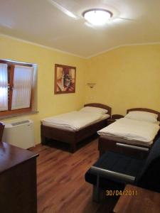 two beds in a room with yellow walls and wooden floors at Arkade turizem in Črniče