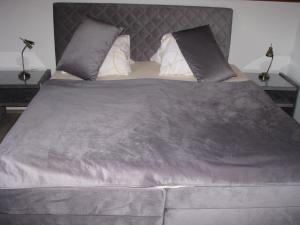 a large bed with a gray blanket and pillows at Aranyszarvas-Goldener Hirsch Pension in Zalakaros