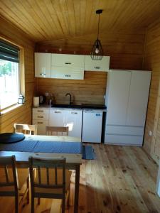 a kitchen with white cabinets and a table with chairs at Domki Orla na Mazurach in Pasym