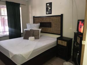 a bedroom with a large white bed with a television at Kaste Guesthouse Secunda in Secunda