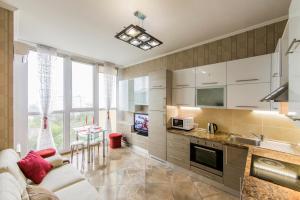 a kitchen with white cabinets and a couch and a table at Rent-Kiev 2 min metro Chernihivska Lux in Kyiv