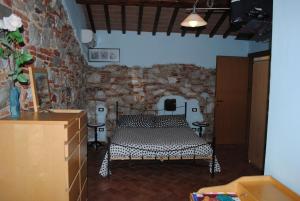 a bedroom with a bed and a stone wall at Podere San Paolo in San Giuliano Terme