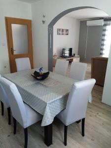 a dining room table with white chairs and a table cloth at Apartment Darinka in Šibenik