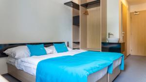 sypialnia z dużym łóżkiem i niebieskim kocem w obiekcie Hotel AquaCity Riverside w Popradzie