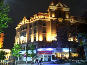 un grande edificio è illuminato di notte di Qingdao Hua Qi Kaiserdom Hotel a Qingdao