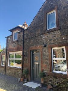 una antigua casa de ladrillo con puerta y ventanas en Fox Cottage en Moffat