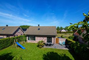 a house with a playground in the yard at Friesland Villa & Blick auf den Horizont in Tzummarum