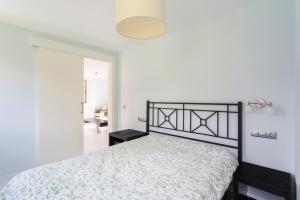 1 dormitorio con 1 cama con colcha blanca en Housingcoruña Apartamento Playa Miño 02, en Miño