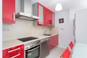 una cocina con armarios rojos y fregadero en Housingcoruña Apartamento Playa Miño 02, en Miño