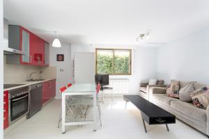cocina y sala de estar con armarios rojos y sofá en Housingcoruña Apartamento Playa Miño 02, en Miño
