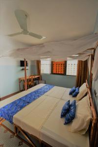 ein Schlafzimmer mit einem Bett mit blauen Kissen darauf in der Unterkunft B&B Chez Rita in Cotonou
