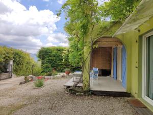 una casa verde con una mesa y una silla en un porche en Bambou entre Mer et Montagnes, en Châteauneuf