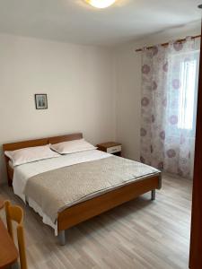 a bedroom with a bed and a window at Apartmani Denona Centar in Novalja