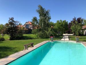 a swimming pool with a bench next to a house at Patrimonium Wellness Apartments in Tiszaszentimre