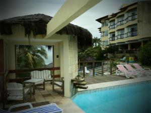 a resort with a pool and chairs and a building at Setiba Pousada Park in Guarapari