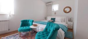 a bedroom with a bed and two blue chairs at Adria Apartments and Rooms in Dubrovnik