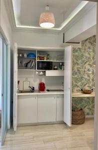 a kitchen with white cabinets and a red appliance at White Tower Mamaia - Private Apartment in Mamaia