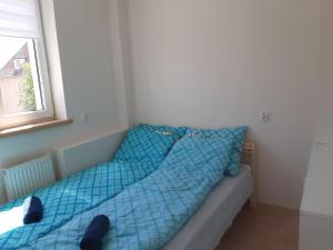 a bed with a blue comforter in a room at Mieszkanie przy Westerplatte in Giżycko