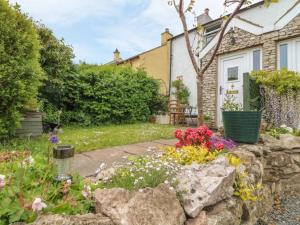 a garden with flowers and a stone wall at Sunnybank Cottage in Ulverston
