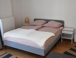 een bed met roze en witte lakens en een bijzettafel bij DOM APARTS in Keulen