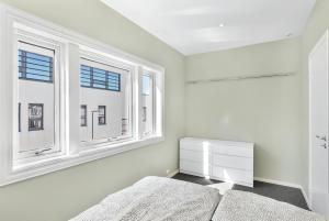 a white bedroom with two windows and a bed at Central Studio Apartment Apt 202 in Stavanger